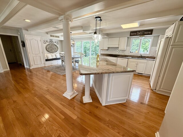 1337 Stratford Dr, Piqua, OH 45356 - kitchen with ornate columns, light wood-style floors, tasteful backsplash, white cabinets, and beam ceiling