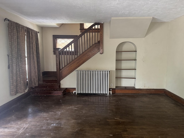 1108 N Fountain Blvd, Springfield, OH 45504 - unfurnished living room with radiator, a textured ceiling, stairway, and wood finished floors