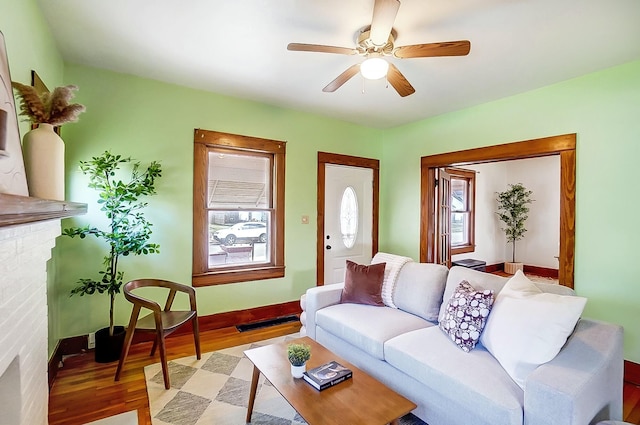 living room with plenty of natural light, light wood-style flooring, baseboards, and ceiling fan