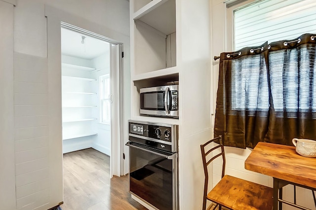 kitchen featuring stainless steel microwave, wood finished floors, and black oven