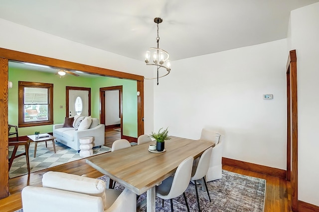 dining room featuring a notable chandelier, wood finished floors, and baseboards