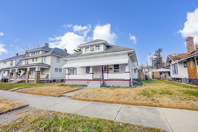 view of front of house featuring covered porch, a front yard, fence, and a residential view