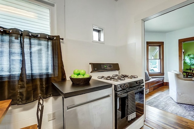 kitchen featuring a wealth of natural light, wood finished floors, and white gas range