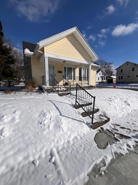 snow covered rear of property featuring covered porch