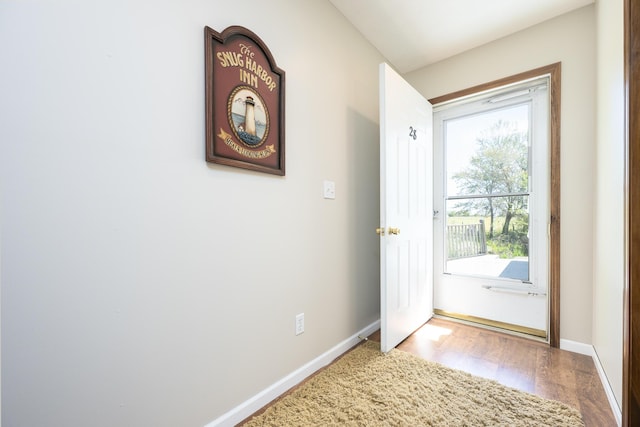 doorway featuring baseboards and wood finished floors