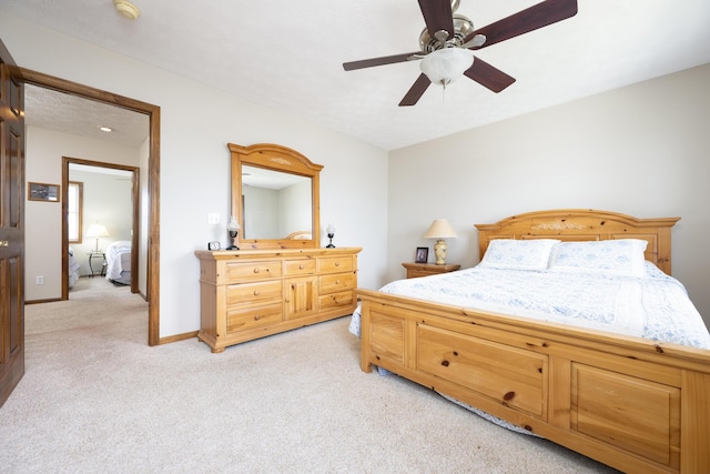bedroom featuring light colored carpet, a ceiling fan, and baseboards