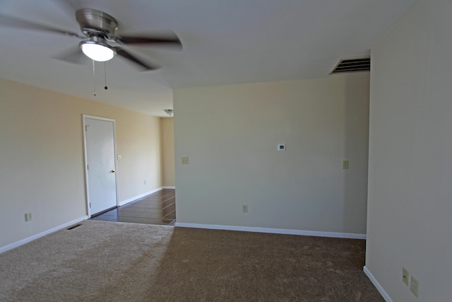 spare room featuring dark colored carpet and ceiling fan