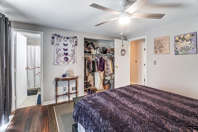 bedroom featuring ceiling fan, connected bathroom, wood finished floors, baseboards, and a closet