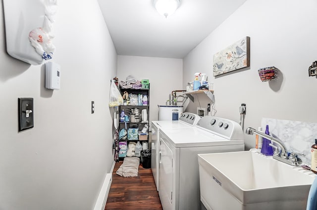 laundry area with dark wood finished floors, washing machine and dryer, a sink, laundry area, and baseboards