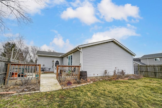 back of property with a fenced backyard, a lawn, and a wooden deck