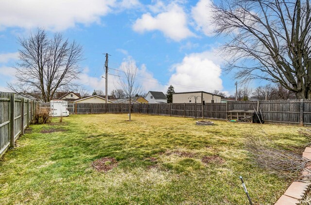 view of yard featuring an outbuilding, a fenced backyard, and a storage unit