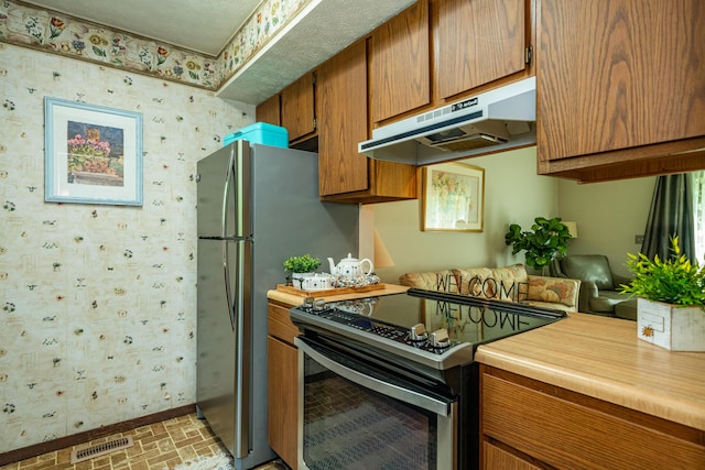 4321 Frontenac Dr, Beavercreek, OH 45440 - kitchen featuring electric range, under cabinet range hood, wallpapered walls, light countertops, and brown cabinets