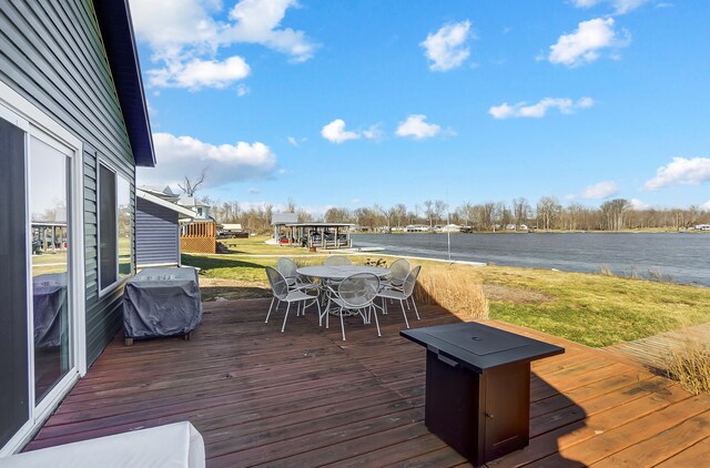 7748 Walnut St, Russells Point, OH 43348 - deck with outdoor dining space, a lawn, a water view, and a grill