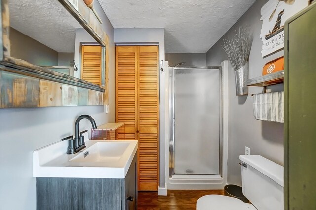 7748 Walnut St, Russells Point, OH 43348 - bathroom featuring toilet, a stall shower, wood finished floors, a textured ceiling, and vanity