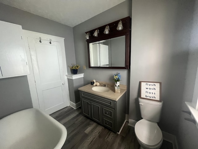 bathroom featuring hardwood / wood-style flooring, vanity, toilet, and a tub