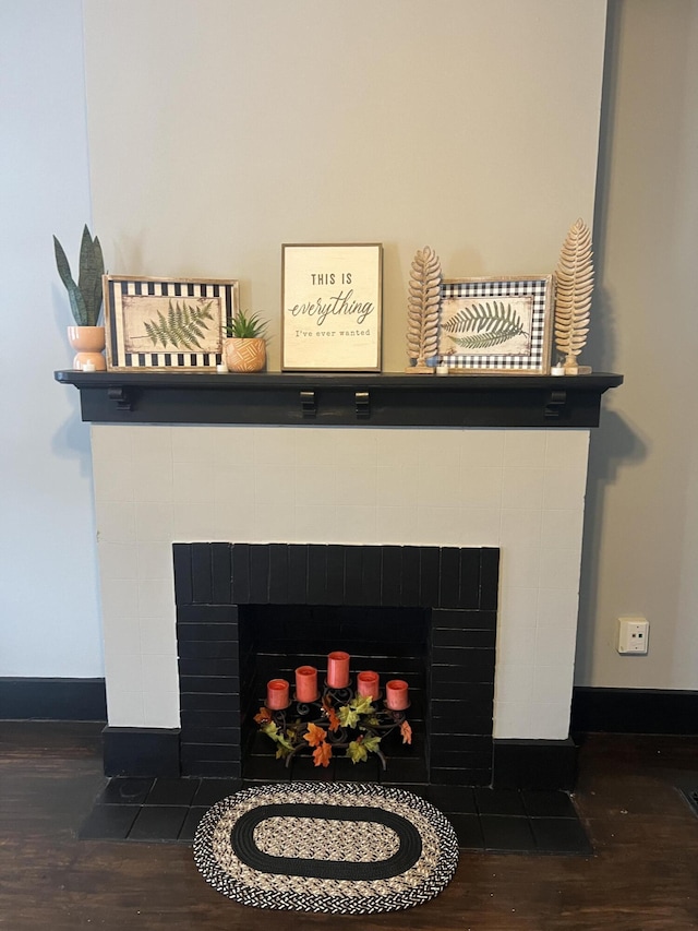 room details featuring a tiled fireplace and hardwood / wood-style flooring