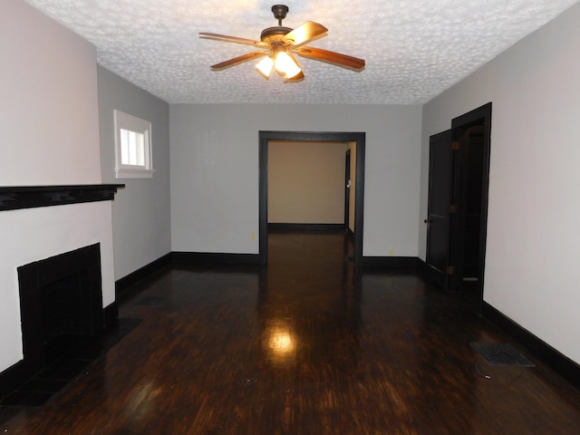 unfurnished living room featuring ceiling fan, dark hardwood / wood-style floors, and a textured ceiling