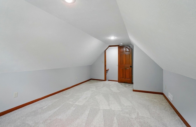 additional living space featuring vaulted ceiling, light carpet, baseboards, and recessed lighting