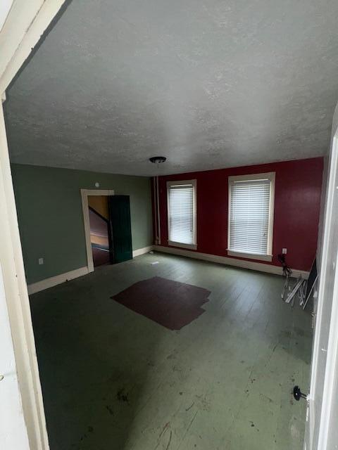 unfurnished living room with baseboards and a textured ceiling