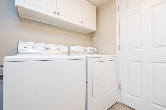 laundry room featuring light wood-type flooring, washer and clothes dryer, and cabinet space