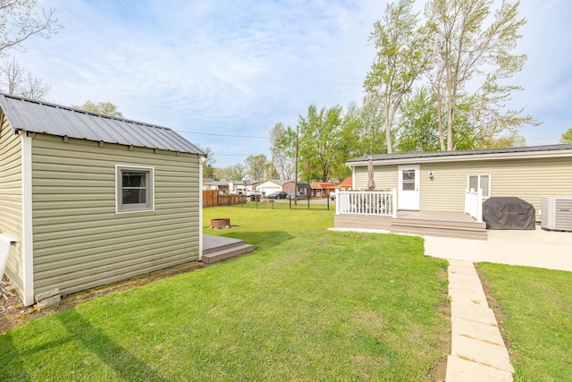 view of yard with central AC unit, fence, an outbuilding, and a wooden deck