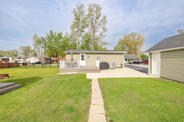 back of property featuring a yard, a deck, fence, and a patio area