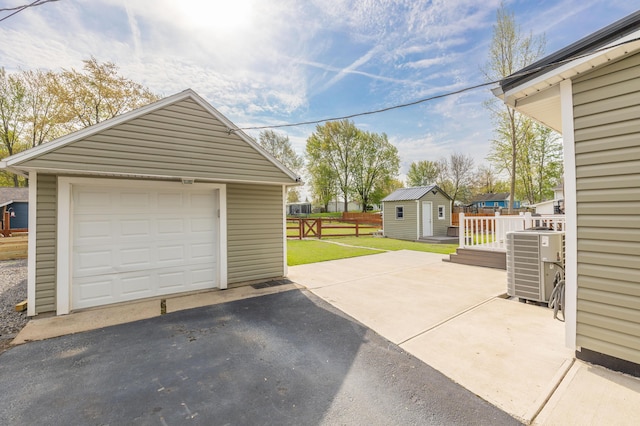 detached garage with driveway and central AC unit