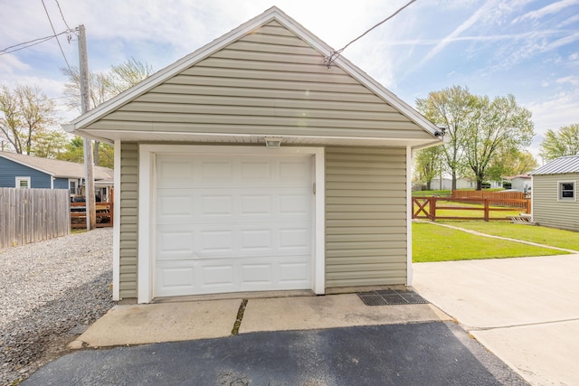 detached garage featuring fence and driveway