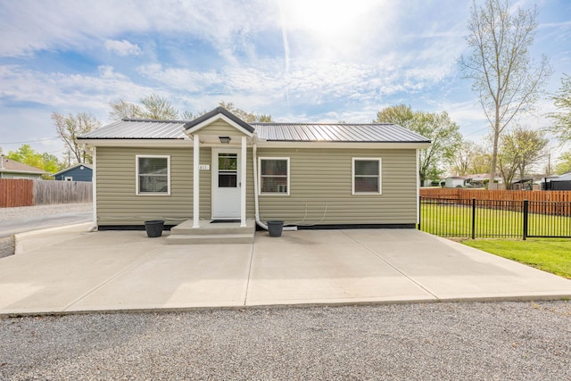 view of front of house featuring fence, a patio, a front lawn, and metal roof