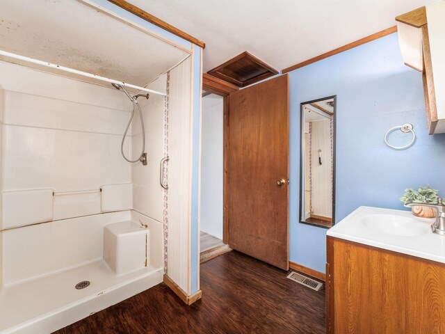 full bath featuring wood finished floors, a shower stall, baseboards, and vanity