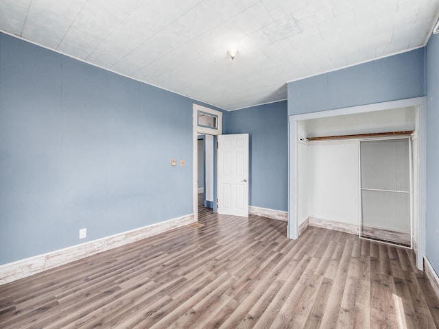 unfurnished bedroom with wood finished floors, a closet, and baseboards