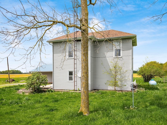 back of house featuring a lawn and a shingled roof