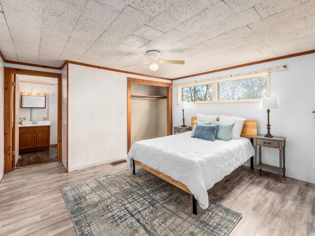 bedroom with crown molding, light wood finished floors, a ceiling fan, and a sink