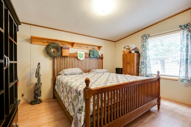 bedroom with crown molding, a textured ceiling, and wood finished floors