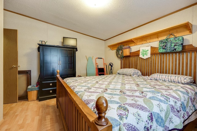 bedroom with light wood-style floors, ornamental molding, vaulted ceiling, and a textured ceiling