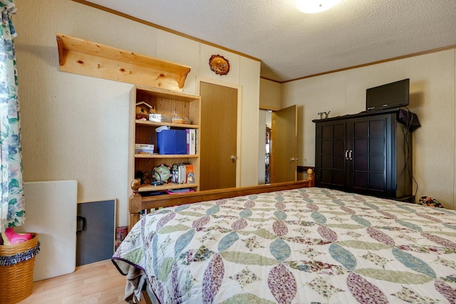 bedroom with a textured ceiling, wood finished floors, and crown molding