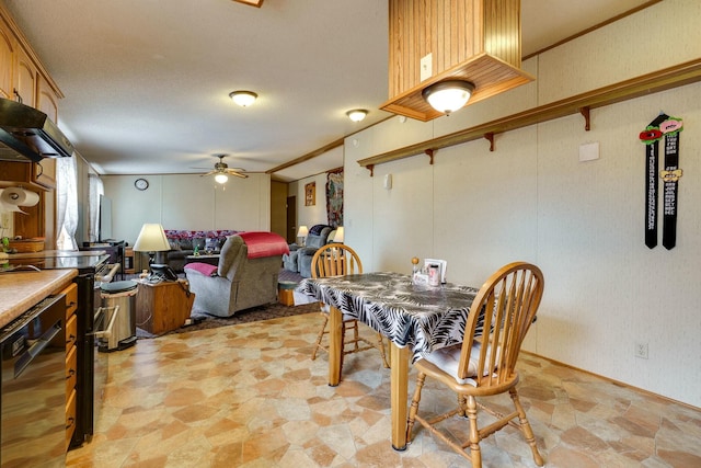 dining room with a ceiling fan, stone finish floor, and ornamental molding