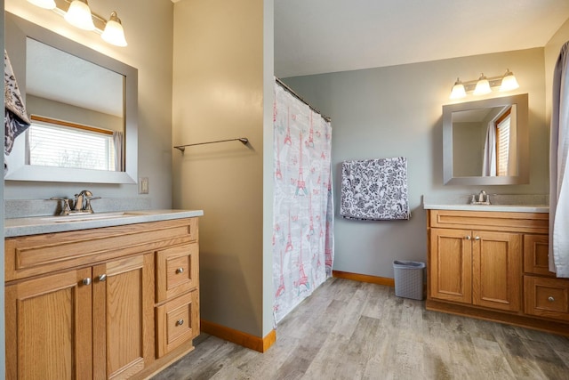 bathroom with a sink, wood finished floors, two vanities, and baseboards