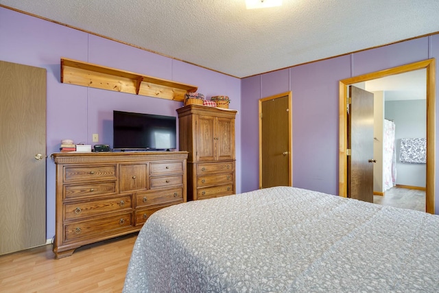 bedroom with light wood-style floors and a textured ceiling