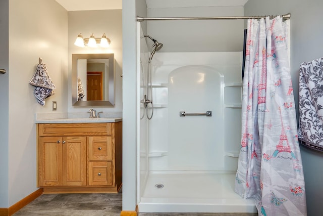 bathroom featuring a shower with curtain, baseboards, wood finished floors, and vanity