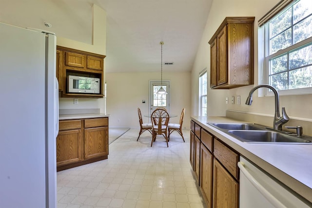 kitchen featuring a sink, brown cabinets, white appliances, and light countertops