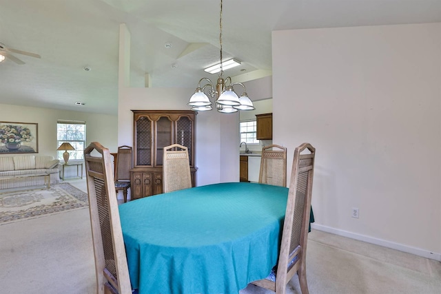 dining space with baseboards, light carpet, a healthy amount of sunlight, and ceiling fan with notable chandelier