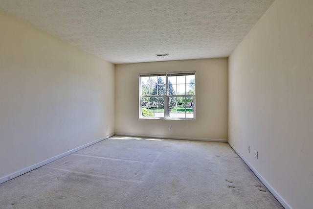 spare room featuring a textured ceiling, visible vents, baseboards, and carpet
