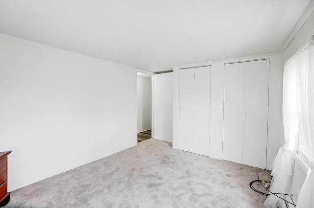 unfurnished bedroom featuring two closets and light colored carpet