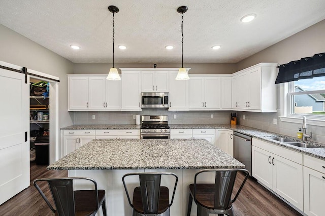 2306 Larkspur Dr, Troy, OH 45373 - kitchen featuring appliances with stainless steel finishes, a breakfast bar area, dark wood-style flooring, a kitchen island, and a textured ceiling