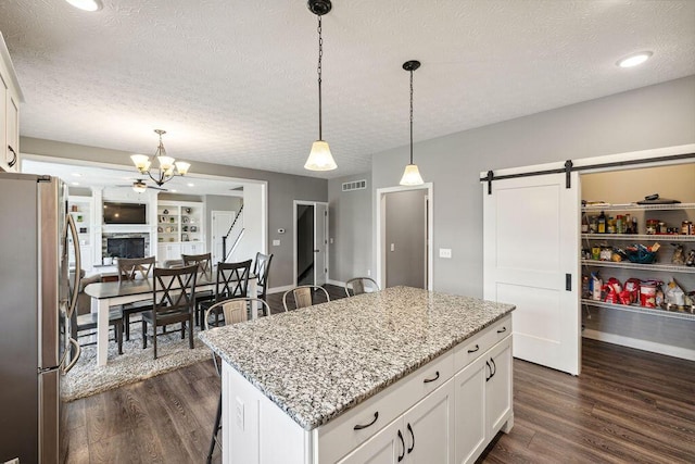 2306 Larkspur Dr, Troy, OH 45373 - kitchen with freestanding refrigerator, a textured ceiling, a barn door, dark wood finished floors, and a center island