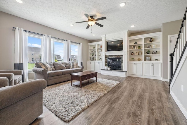 2306 Larkspur Dr, Troy, OH 45373 - living area featuring a ceiling fan, a stone fireplace, wood finished floors, stairway, and a textured ceiling