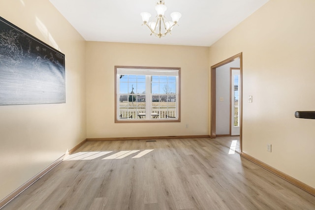 unfurnished room with light wood-style flooring, baseboards, and an inviting chandelier