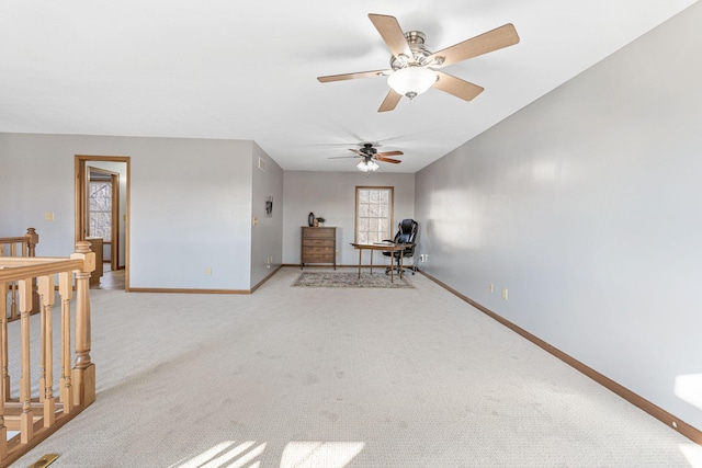 interior space with a ceiling fan, an upstairs landing, baseboards, and light carpet