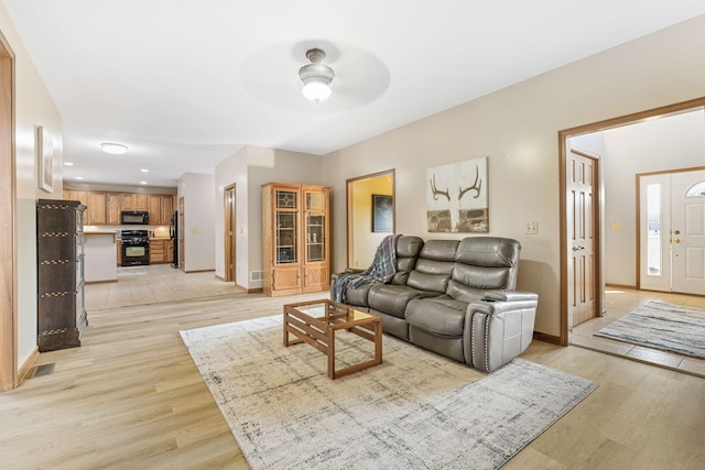 living room with baseboards, light wood-type flooring, and ceiling fan